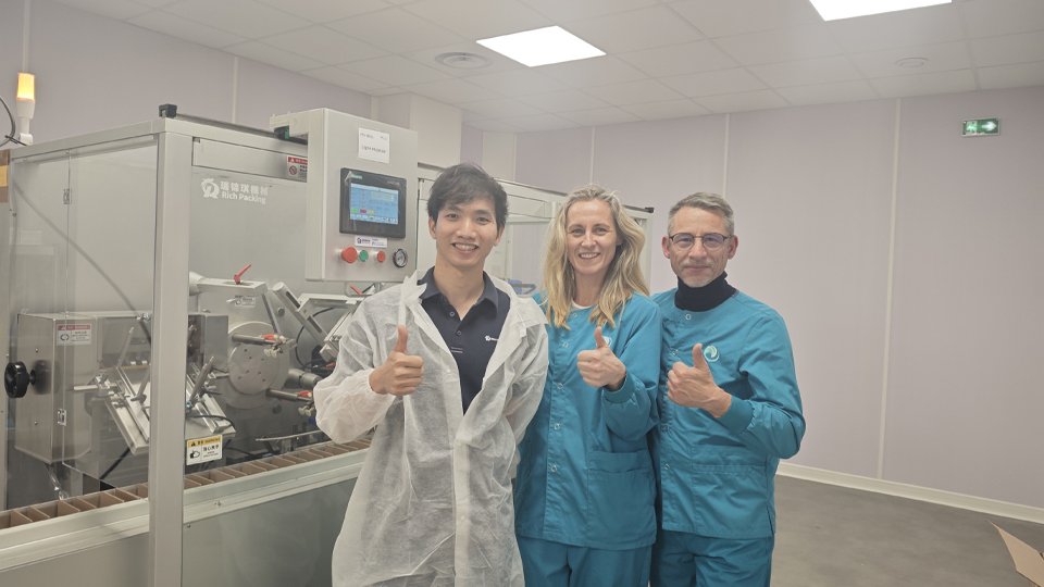 Henry and French clients in front of the cartoning machine